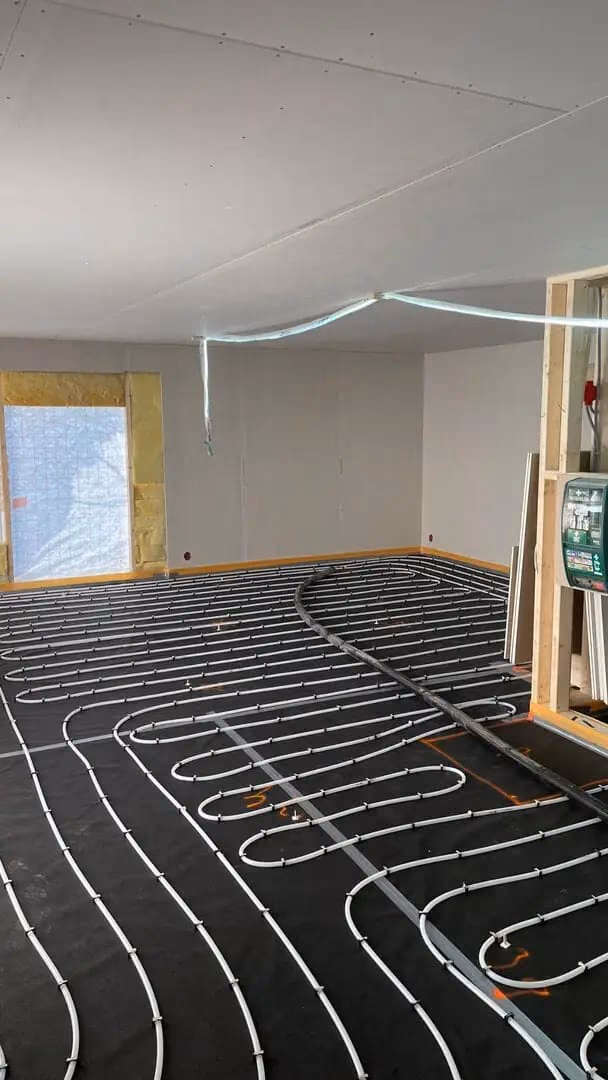 Varmepumpeinstallasjon med gulvvarmesystem under oppussing i et rom, klar for ferdigstillelse. Perfekt for energieffektiv oppvarming og komfort.