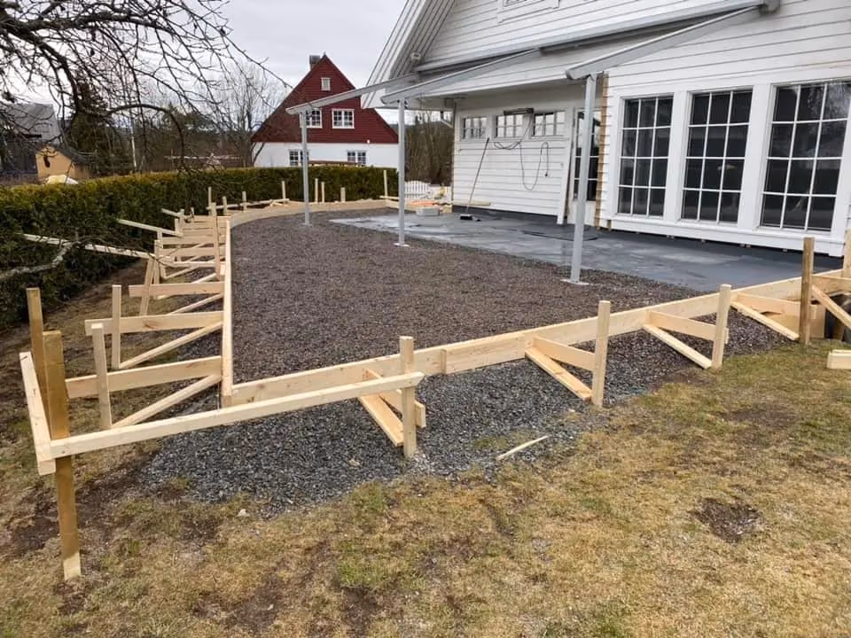 Utendørs hagearbeid med oppbygde trekonstruksjoner for terrasse eller gangvei, utført av Bærum Bygg og Graveservice, med fokus på kvalitet og holdbarhet.