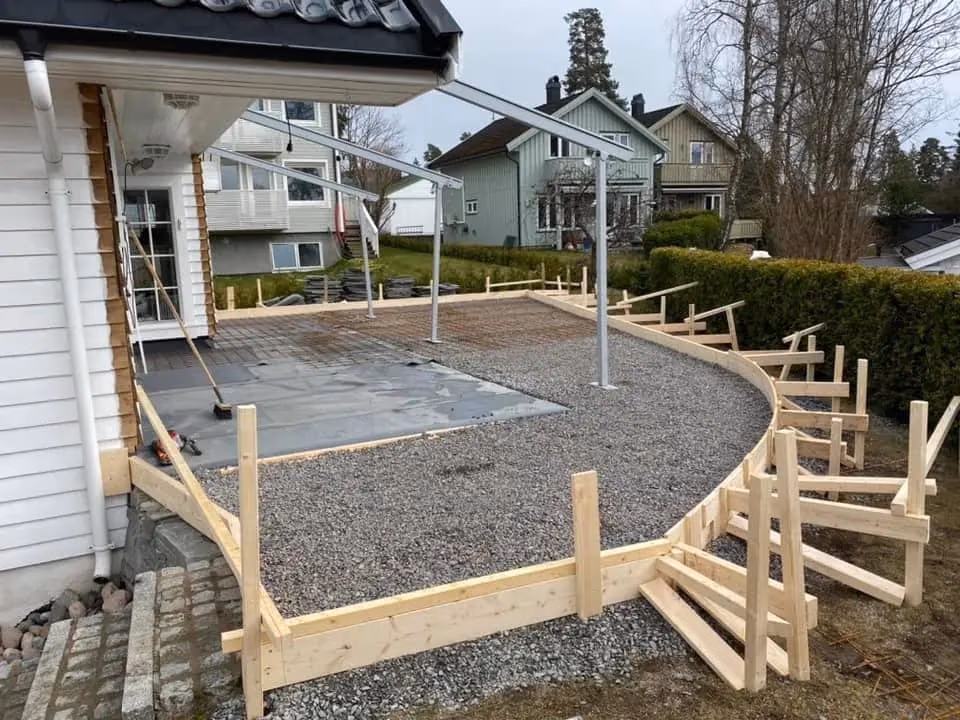 Fasade av oppkjørsel under bygging med grus og treverk, klar for støping av betong, utført av Bærum Bygg og Graveservice, spesialister på oppkjørsel og gravearbeid.