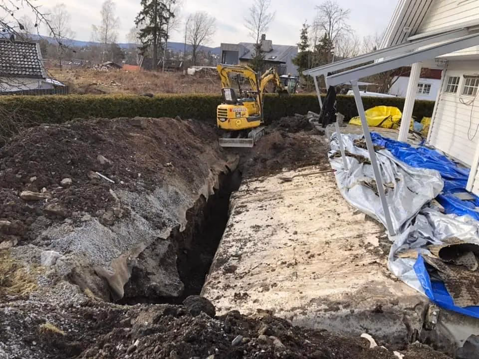 Bilde av gravearbeid med minigraver som utfører grunnarbeid ved bolig, med fokus på utgraving og jordarbeid for bygg- og graveprosjekter.