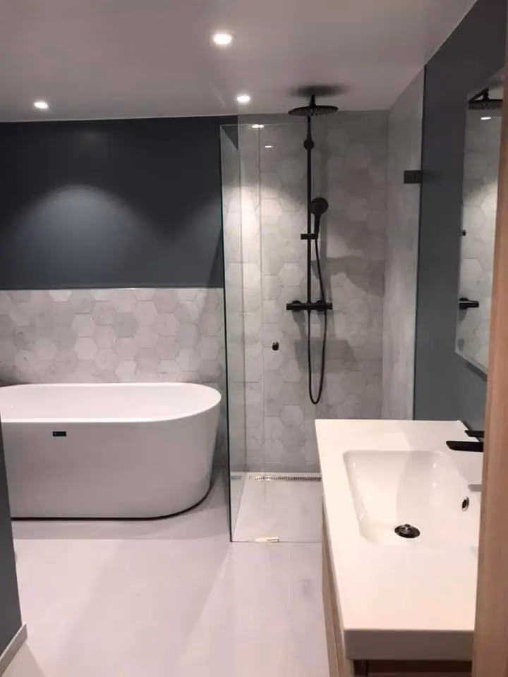 Bilde av moderne bad med badekar, dusj og vask, utført av Bærum Bygg og Graveservice, spesialisert på bygg- og gravearbeid, badrenovering og våtrom.
