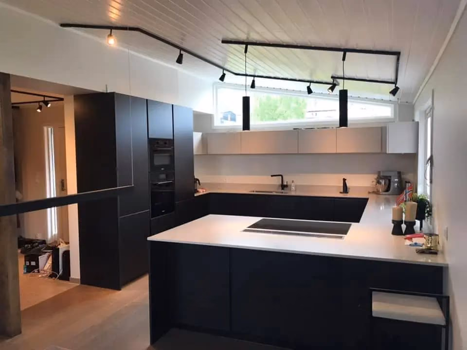 Moderne kjøkken med svarte skap, hvit benkeplate og store vinduer, perfekt for oppussing og kjøkkenrenovering i Bærum. Ideell for hjem med fokus på stil og funksjonalitet.