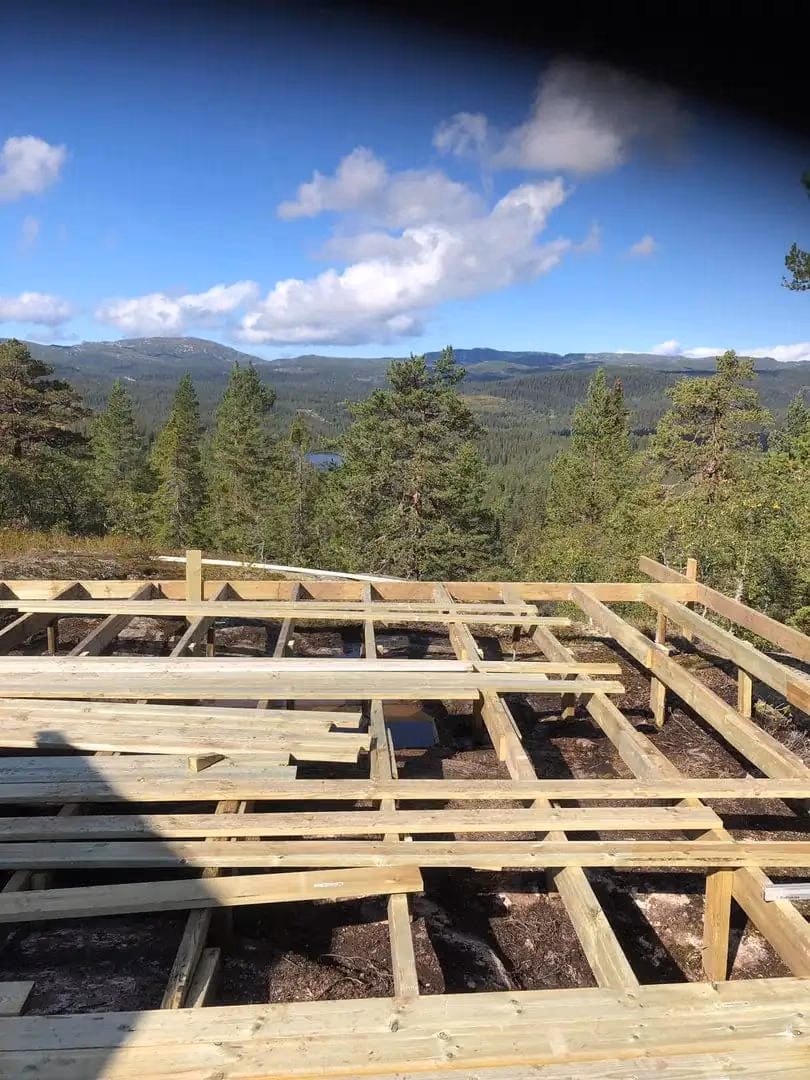 Treterrasse under bygging i Bærum med utsikt over skog og fjell, fokus på bygg og gravearbeid, profesjonell utendørs konstruksjon, Bærum Bygg og Graveservice.