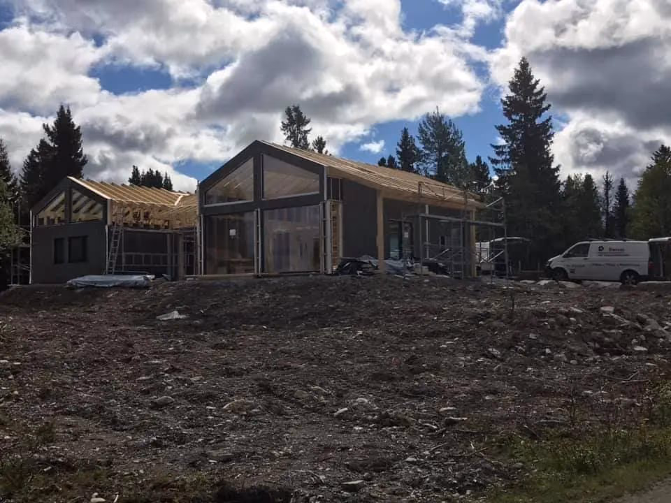 Nybygde moderne hus i Bærum under konstruksjon, med treverk og store vinduer, omgitt av skog, klar for innflytting, utført av Bærum Bygg og Graveservice.