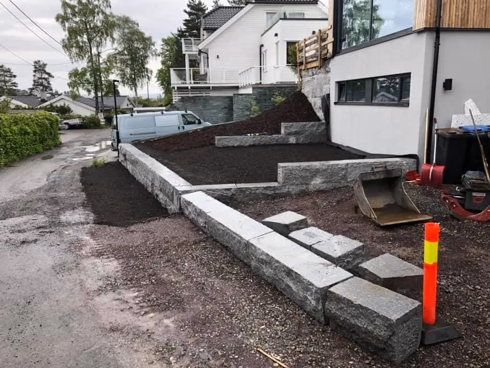 Bilde av opparbeidet hage med ny støttemur og gangsti, utført av Bærum Bygg og Graveservice. Profesjonell hage- og gravearbeid i Bærum, med fokus på kvalitet og holdbarhet.