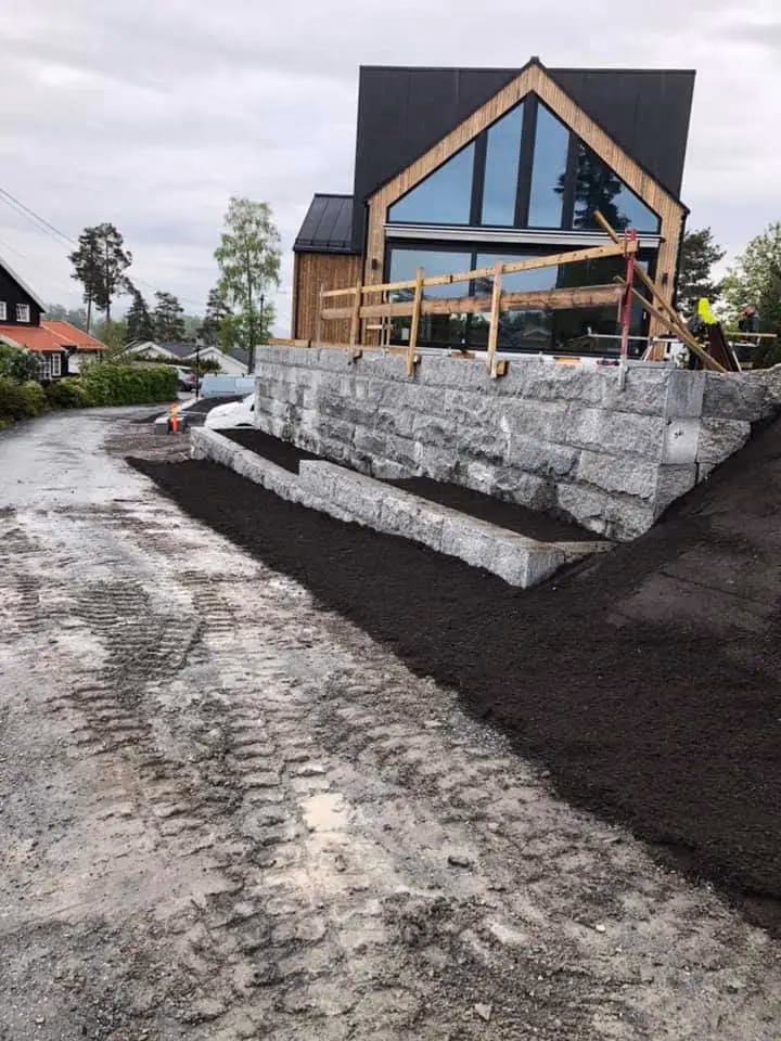 Nybygget hus med store glassvinduer og trefasade, omgitt av byggeområde med jord og grus, klar for ferdigstillelse, i Bærum.