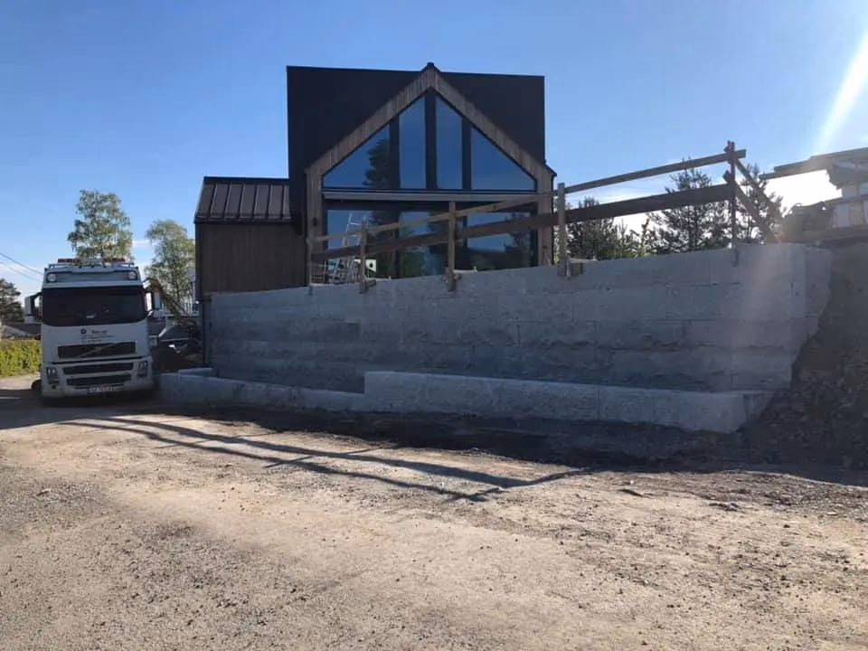 Nybygget moderne hus med store glassvinduer og trefasade, ferdigstilt av Bærum Bygg og Graveservice, med fokus på bygging og gravearbeid i Bærum.