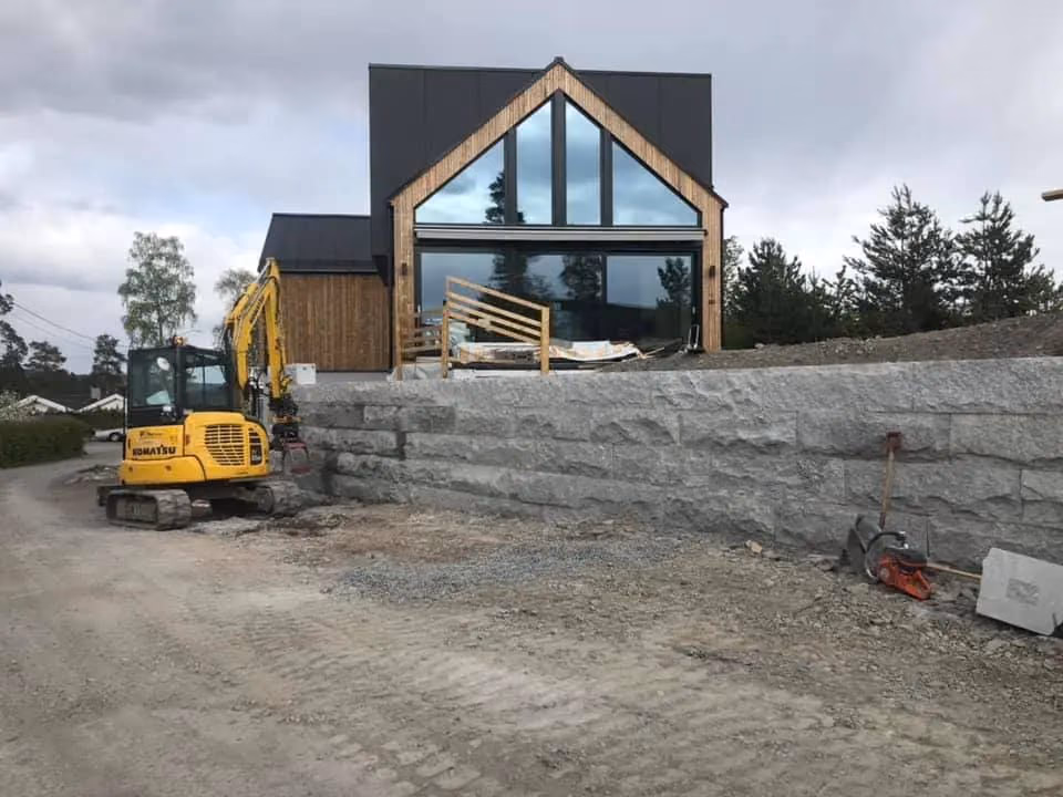 Bilde av et moderne hus under bygging med gravearbeid og utstyr for grunnarbeid, som viser Bærum Bygg og Graveservice sin ekspertise innen bygg- og gravearbeid i Bærum.